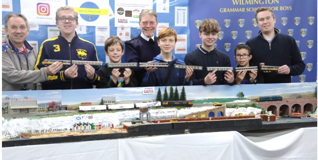 A group of people holding a model train

Description automatically generated